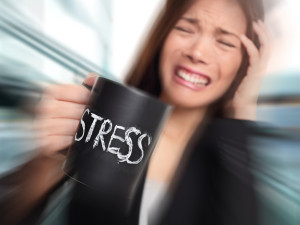 Stress - business person stressed at office. Business woman holding coffee cup with STRESS written. Overworked and over caffeinated female businesswoman.